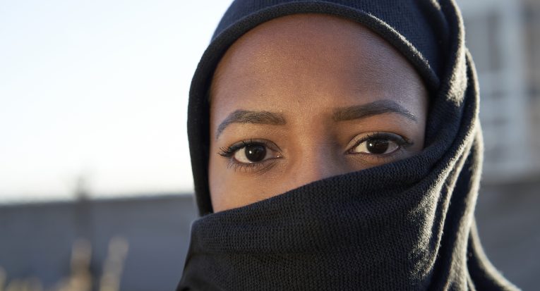 Close-up of face of a young Muslim girl with hijab looking at the camera.