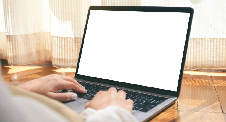 Mockup image of a woman using laptop computer with blank white desktop screen while laying down on the floor with feeling relaxed