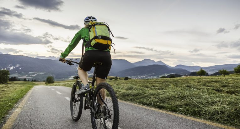 Woman cycling on road, Fondo, Trentino, Italy