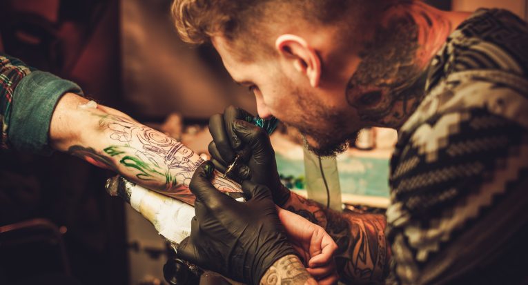 Tattoo artist makes a tattoo on a man's hand