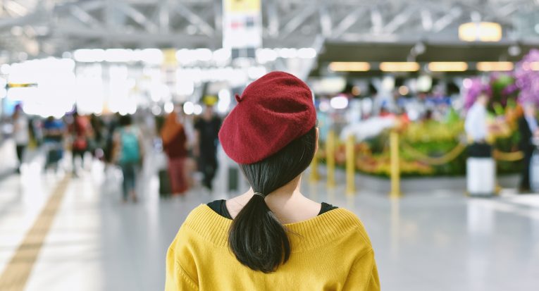 Asian woman standing in trade fair exhibition hall, Blurred background of large crowded people at big event with copyspace.