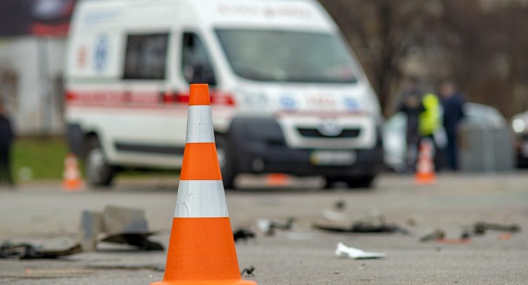 Yellow plastic cone placed on a street at car accident crash site.