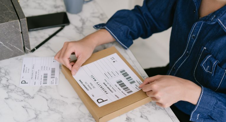 Startup small business SME owner Asian male entrepreneurs packing product shipping order box for dispatching,  labeling delivery package with barcode. Online selling, e-commerce, shipping.Concept.