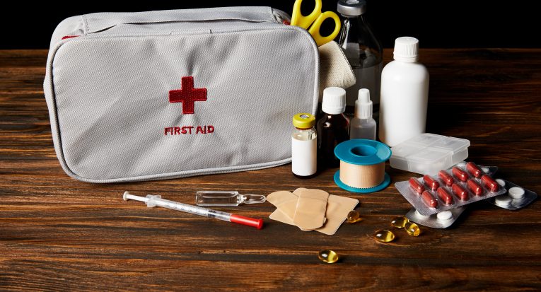 close-up shot of first aid kit with different medicines on wooden tabletop and on black