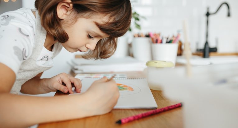 Kids painting watercolor rainbows at table at home. Arts and crafts