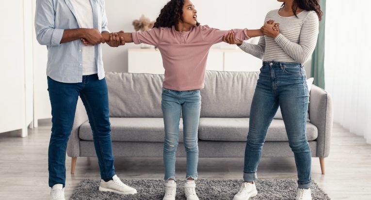 Effects of Divorce on Children. Irritated black man and woman fighting over daughter, angry mother and father having quarrel, pulling girl's hands in different directions. Problem Of Child Custody