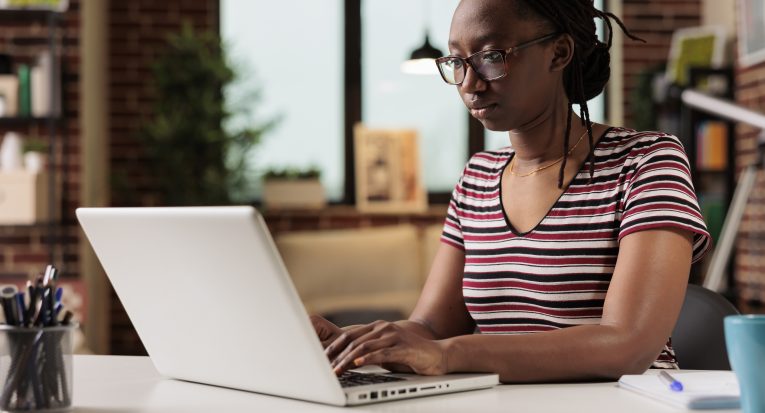 Freelancer working, typing on laptop keyboard, searching information on internet in home office. Employee writing message on computer, copywriting, sitting at workplace desk