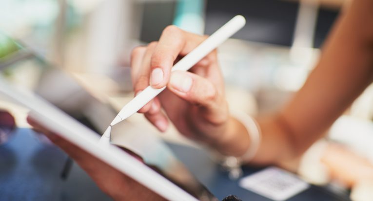 Detail of unrecognizable person using tablet with pencil in cafeteria